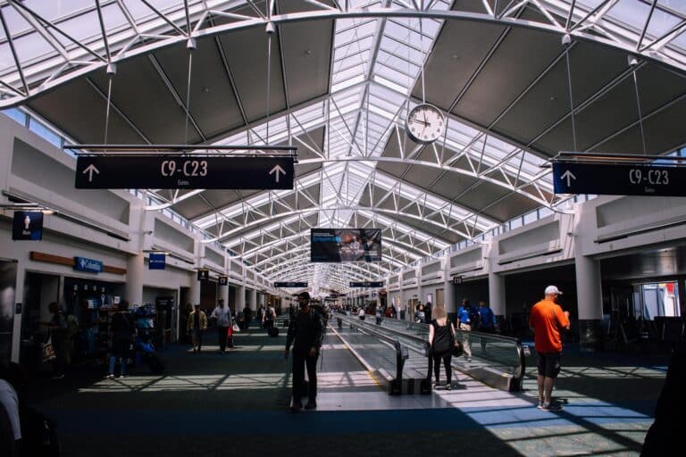 Spacious airport terminal with moving walkway and travelers, showcasing modern architecture.