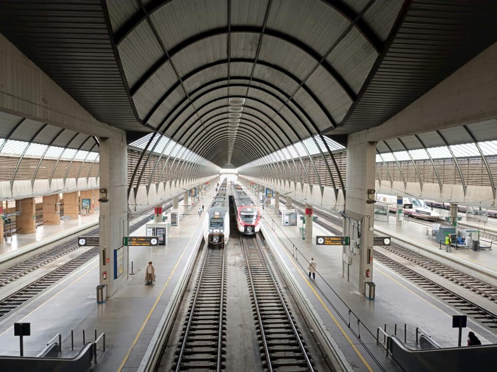 Vibrant view of Sevilla's modern train station with trains on tracks.